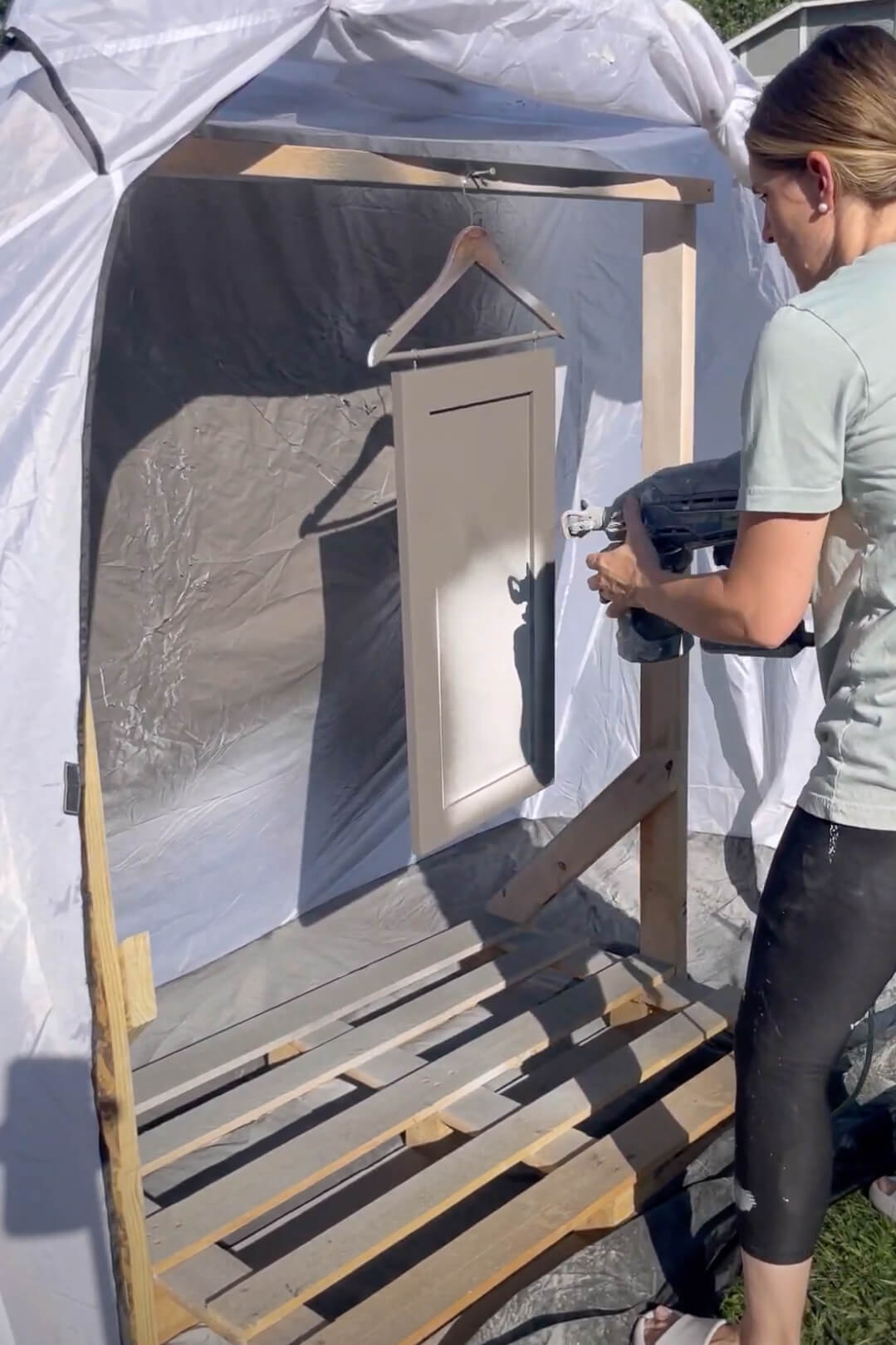 Painting kitchen cabinets with a paint sprayer.